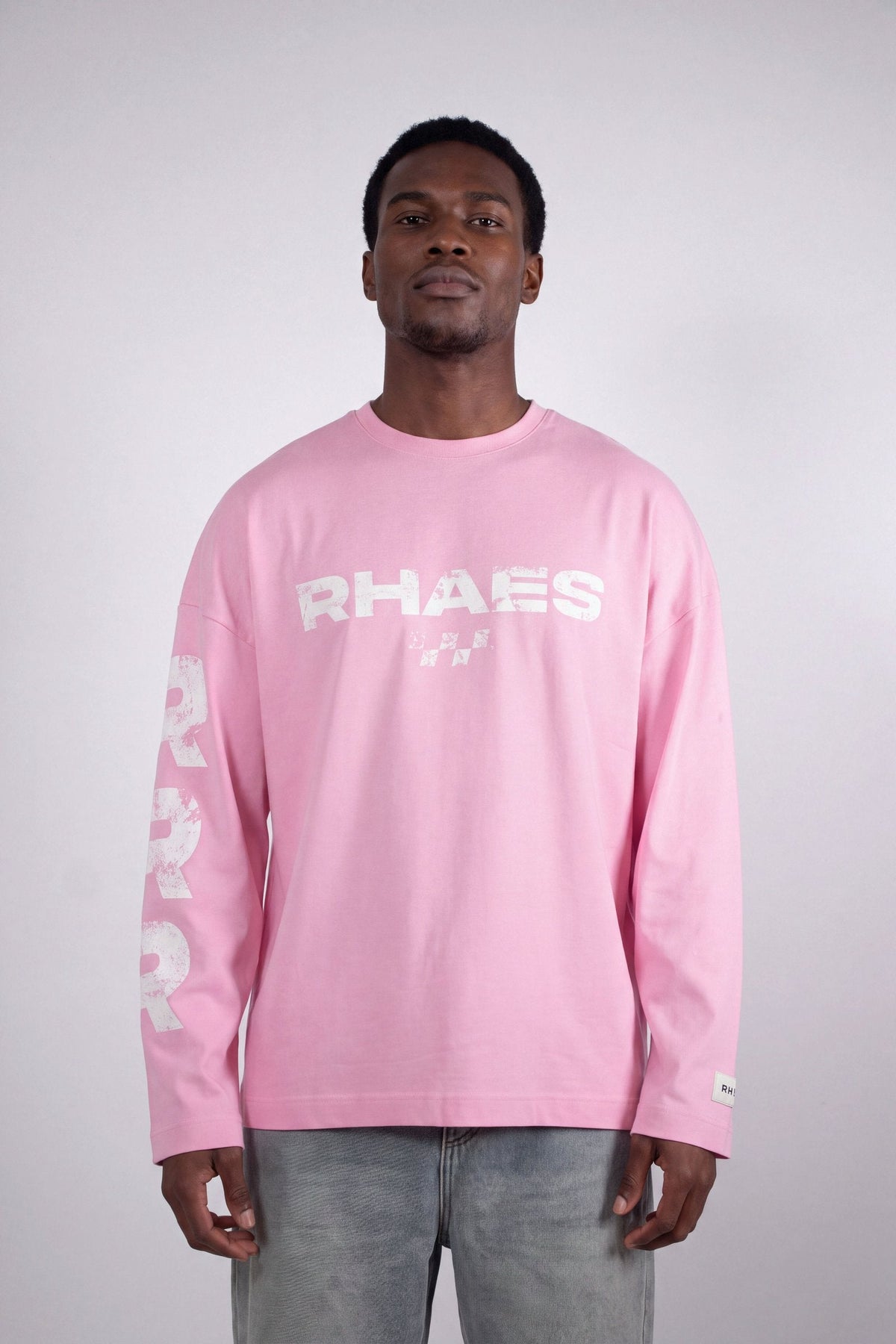 Model wearing RHAES 22 Long Sleeve in Soft Pink — distressed RHAES chest print